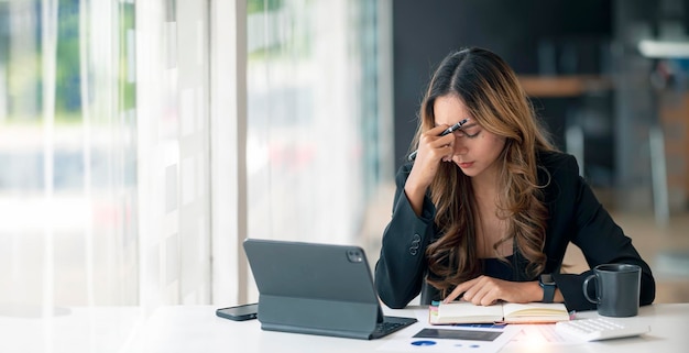 Una mujer de negocios estresada que trabajaba en la oficina con una laptop cerró los ojos y se veía preocupada, cansada y abrumada