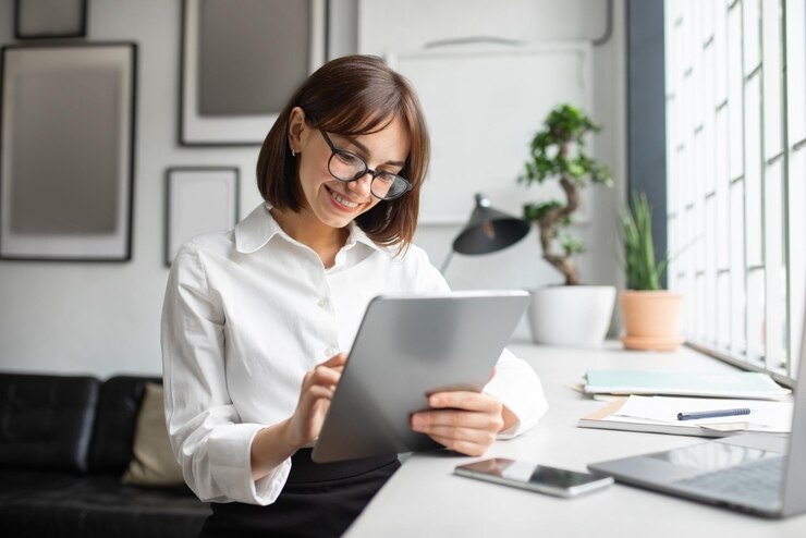 Mujer de negocios europea segura de sí misma que trabaja en línea escribiendo en una tableta para invertir o hablando con