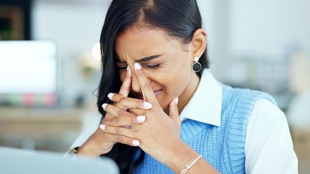 Una mujer de negocios con exceso de trabajo con dolor de cabeza mientras trabaja en su oficina Una mujer corporativa cansada o estresada con dolor en el lugar de trabajo Una joven empresaria que sufre de fatiga