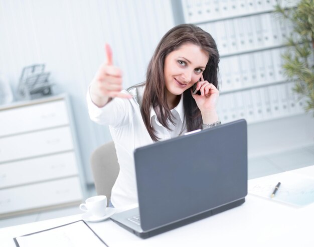 Mujer de negocios exitosa mostrando el pulgar hacia arriba en el lugar de trabajo