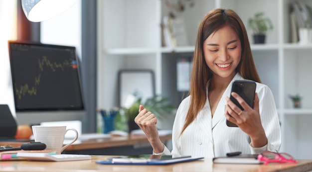 Mujer de negocios Felicitaciones por la buena noticia de obtener ganancias del comercio de acciones a través del teléfono móvil