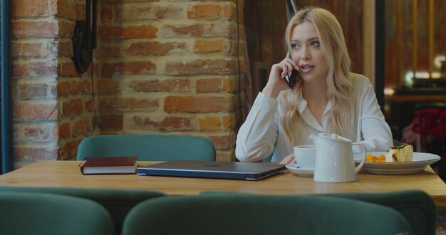 Mujer de negocios feliz hablando con smartphone en café.