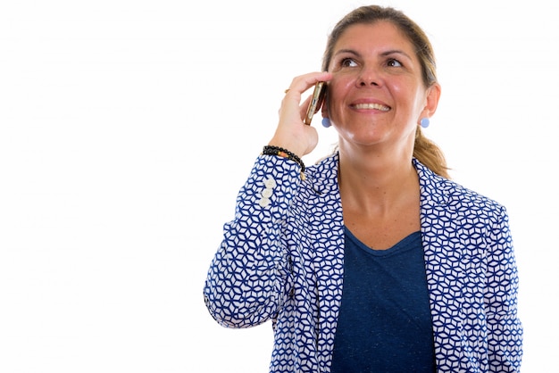 Mujer de negocios feliz madura pensativa sonriendo mientras habla por teléfono móvil