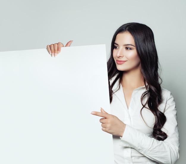 Mujer de negocios feliz morena sonriendo mostrando fondo de banner de papel en blanco blanco y señalando el concepto de educación y negocios de mujer estudiante inteligente