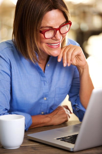 Mujer de negocios feliz sentado en el escritorio con la computadora portátil