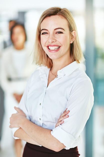 Mujer de negocios feliz, sonriente y confiada, de pie con los brazos cruzados en una oficina moderna en el trabajo Retrato de una profesional corporativa positiva, alegre y alegre que trabaja en una empresa nueva
