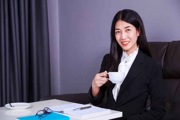 mujer de negocios feliz trabajando y bebiendo una taza de café