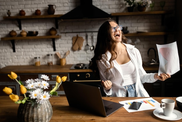 Foto mujer de negocios feliz trabajando desde casa hermosa dama trabajando con documentos en la cocina alta