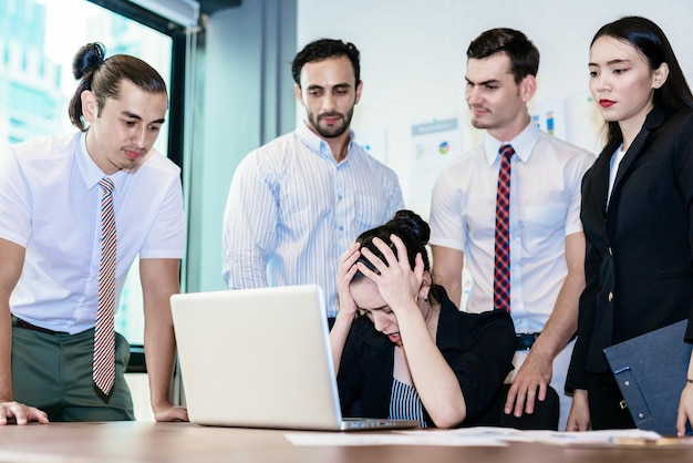 Foto mujer de negocios frustrada usando una computadora portátil mientras explica a sus colegas en una reunión en la sala de juntas