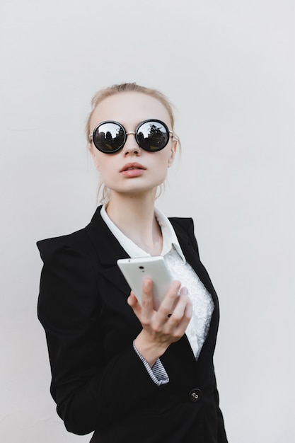 Mujer de negocios con gafas de sol negras y un teléfono en la mano