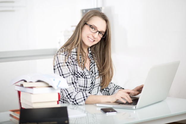 Mujer de negocios hablando al móvil y trabajando en la oficina con laptop