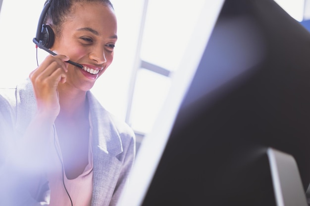 Mujer de negocios hablando en auriculares mientras trabaja en la computadora en el escritorio