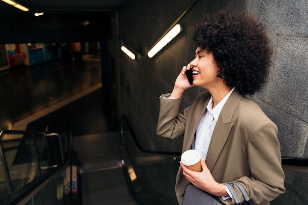 Mujer de negocios hablando por teléfono en la escalera mecánica