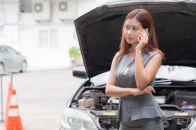 Mujer de negocios hablando por teléfono móvil contra el coche