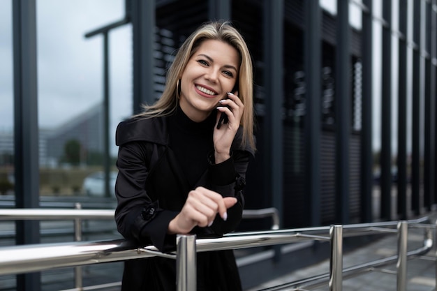 Mujer de negocios hablando por un teléfono móvil con una sonrisa mirando a la cámara en el fondo de un