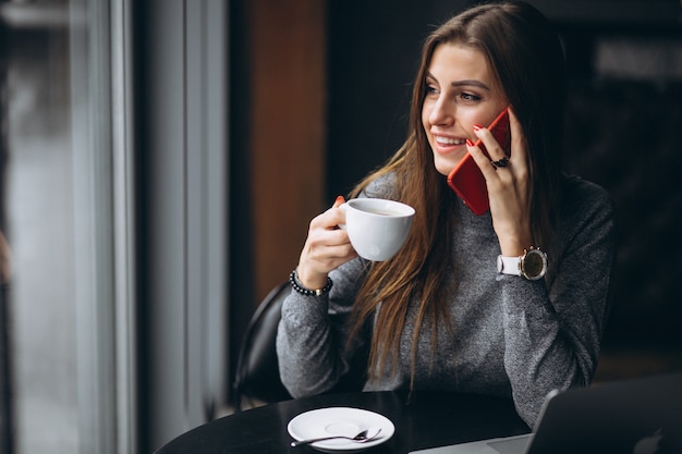 Mujer de negocios hablando por teléfono y tomando café en una cafetería