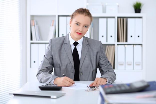 Mujer de negocios haciendo informe calculando o comprobando el saldo