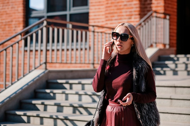 Mujer de negocios hermosa elegante que habla en el exterior propenso móvil