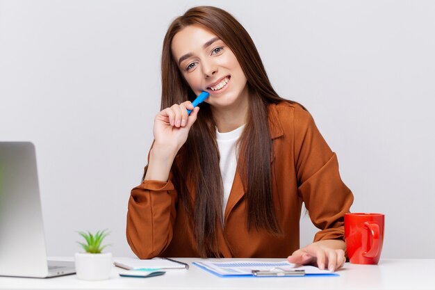 Mujer de negocios hermosa feliz con el portapapeles en la oficina.