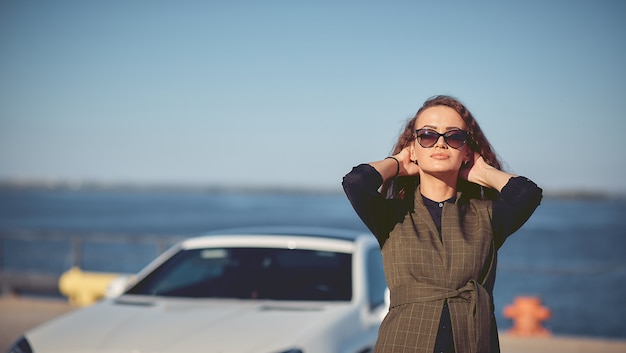 Mujer de negocios hermosa en gafas de sol y traje de negocios en la puesta del sol en el fondo