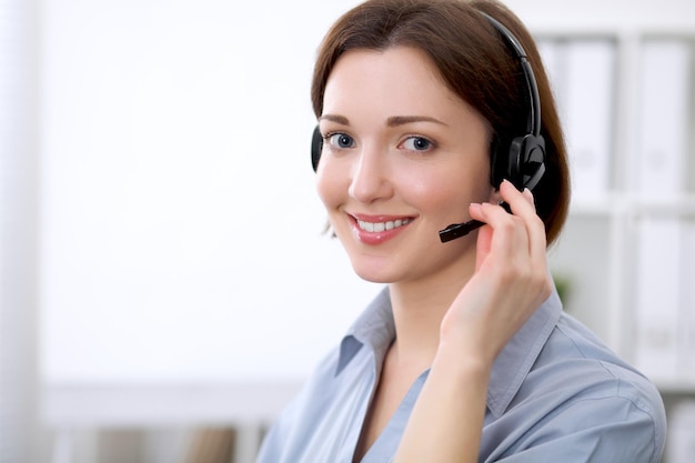 Mujer de negocios hermosa joven en auriculares. Centro de llamadas.