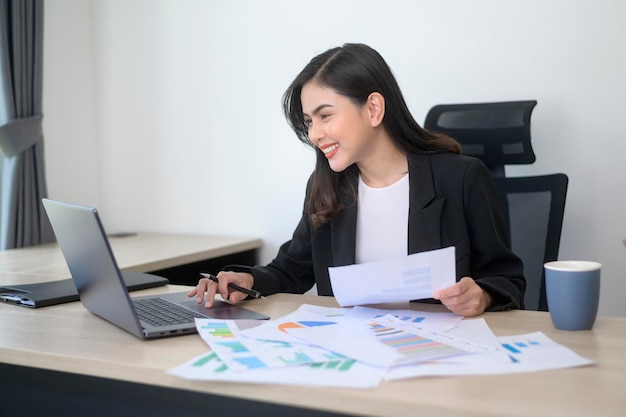 Mujer de negocios hermosa joven que trabaja en la computadora portátil con documentos en la oficina moderna