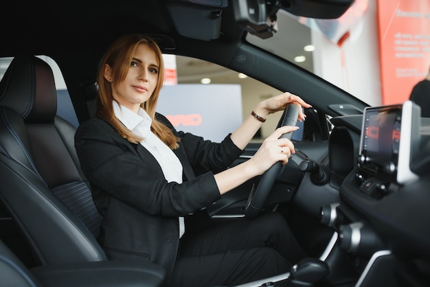 Mujer de negocios hermosa joven sentada en su coche