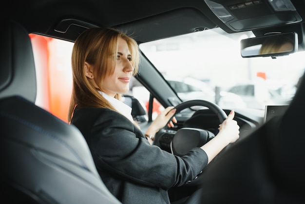 Mujer de negocios hermosa joven sentada en su coche