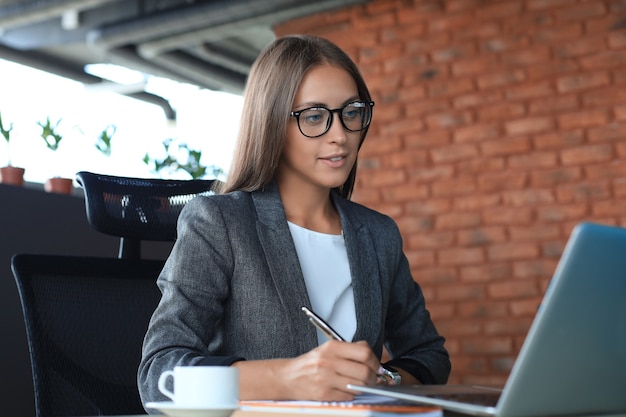 Mujer de negocios hermosa que trabaja en la computadora portátil en la oficina.