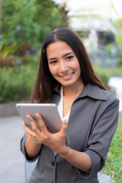 Mujer de negocios hermosa que usa el ipad para el trabajo al aire libre