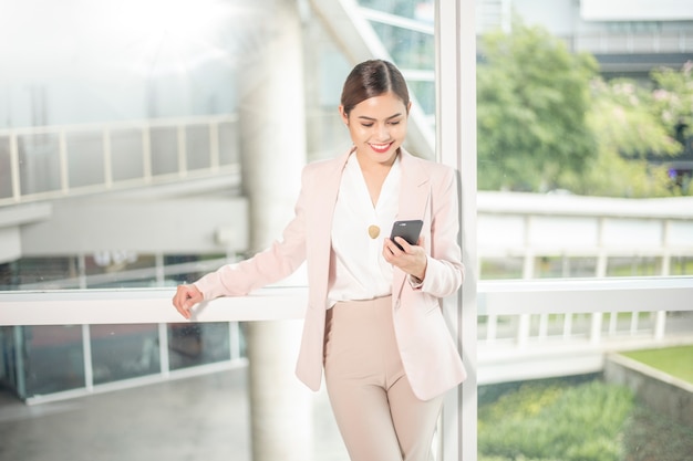 La mujer de negocios hermosa está utilizando el teléfono elegante para el negocio