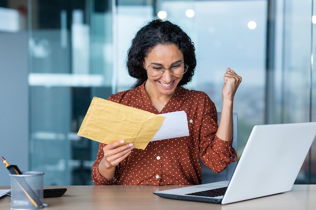 Foto mujer de negocios hispana feliz recibió carta de notificación bancaria en sobre feliz negocio