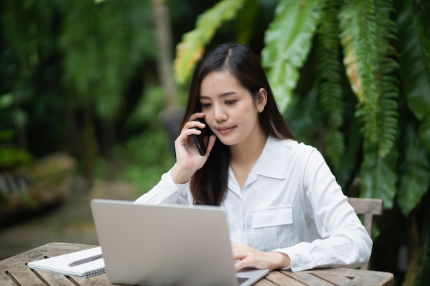 Mujer de negocios independiente que llama a un teléfono inteligente móvil mientras trabaja con un teléfono móvil de una mujer de negocios portátil para llamar a los clientes o comprar en línea Conferencia de conversación de teléfonos inteligentes