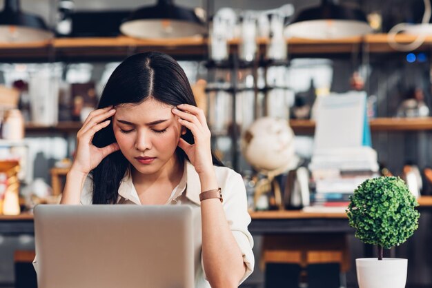 Mujer de negocios independiente que trabaja con una computadora portátil estaba estresada porque el trabajo no se declaró en bancarrota en una cafetería