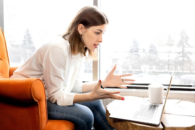 Mujer de negocios irritada que tiene una conferencia en línea con compañeros de trabajo discutiendo problemas laborales