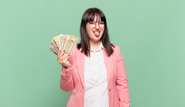 Mujer de negocios joven con actitud alegre, despreocupada y rebelde, bromeando y sacando la lengua, divirtiéndose