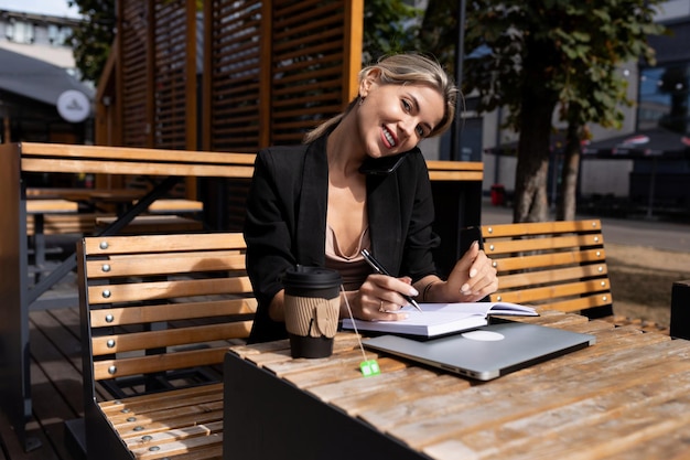 Mujer de negocios joven almorzando en un café de la ciudad con un diario portátil