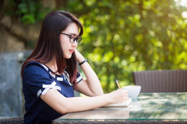 La mujer de negocios joven asiática escribe una nota