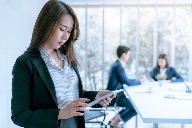 Mujer de negocios joven asiática en usar la tableta para trabajar sobre plan de comercialización