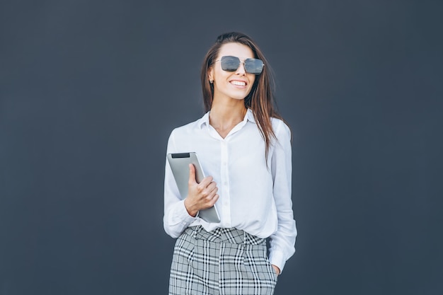 Mujer de negocios joven con café y tableta sobre fondo gris.