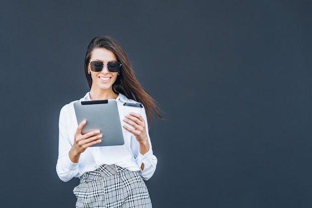 Mujer de negocios joven con café y tableta sobre fondo gris