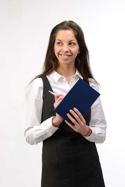 Mujer de negocios joven hermosa con el cuaderno, en la pared blanca