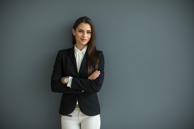 Mujer de negocios joven junto a la pared