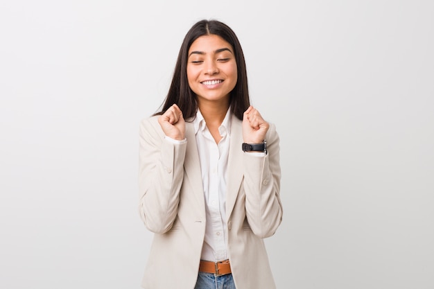 Mujer de negocios joven levantando el puño, sintiéndose feliz y exitoso