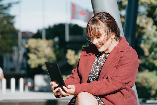 Mujer de negocios joven pelirroja sonriendo y riendo videollamada mientras usa la tableta fuera de la oficina. Copie la imagen del espacio, los negocios y el trabajo en el concepto de oficina. Fuera de la oficina, elegante look moderno.