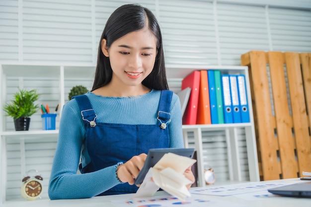 Mujer de negocios joven que calcula el presupuesto familiar, tratando de ahorrar algo de dinero con la factura en papel financiero.