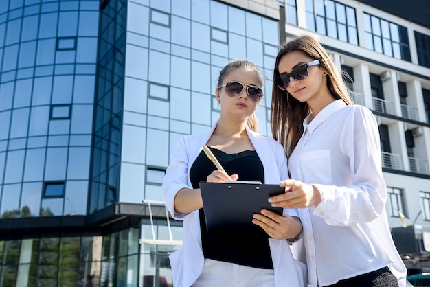 Mujer de negocios joven que firma contrato fuera del centro de negocios en la gran ciudad