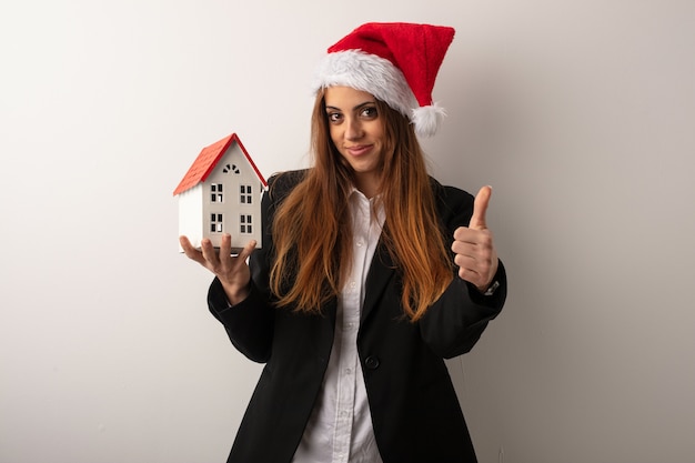 Mujer de negocios joven que lleva el sombrero de santa que celebra día de la Navidad