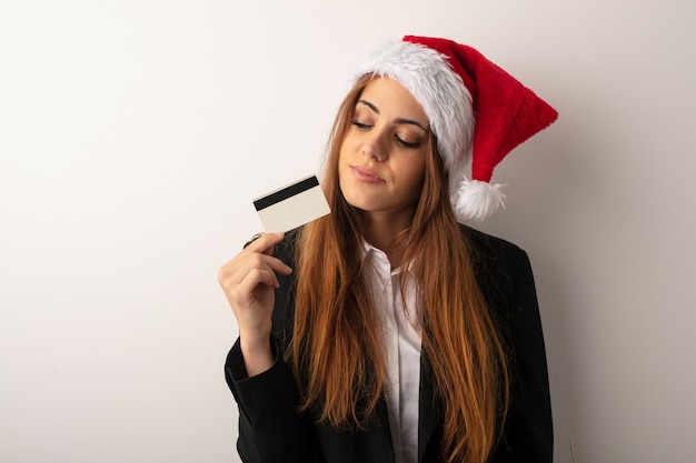 Mujer de negocios joven que lleva el sombrero de santa que celebra día de la Navidad