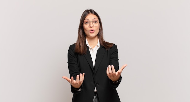 Mujer de negocios joven que se siente extremadamente conmocionada y sorprendida, ansiosa y en pánico, con una mirada estresada y horrorizada